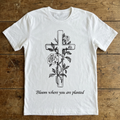 White t-shirt with a cross and floral design on a wooden surface