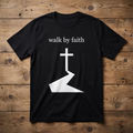Black t-shirt with 'walk by faith' text and cross design on a wooden surface